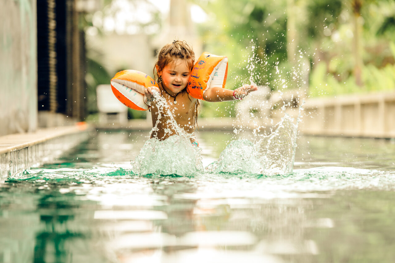 Kind hat Spass bei Wasser spritzen beim sommerlichen Fotoshooting im Pool mit Fotograf Markus Winkelbauer