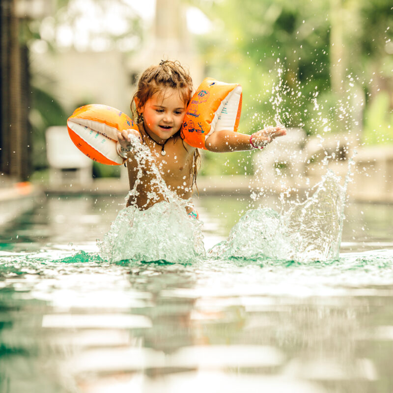 Kind hat Spass bei Wasser spritzen beim sommerlichen Fotoshooting im Pool mit Fotograf Markus Winkelbauer