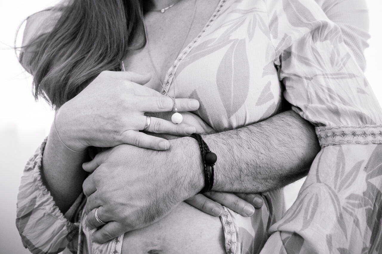 Sich umarmendes Paerchen beim Babybauchshooting als schwarz weiß Foto von Fotograf Markus Winkelbauer