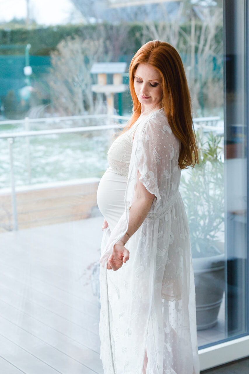 Schwangere Frau fotografiert zu Hause vor der Terrassentuere von Fotograf Markus Winkelbauer